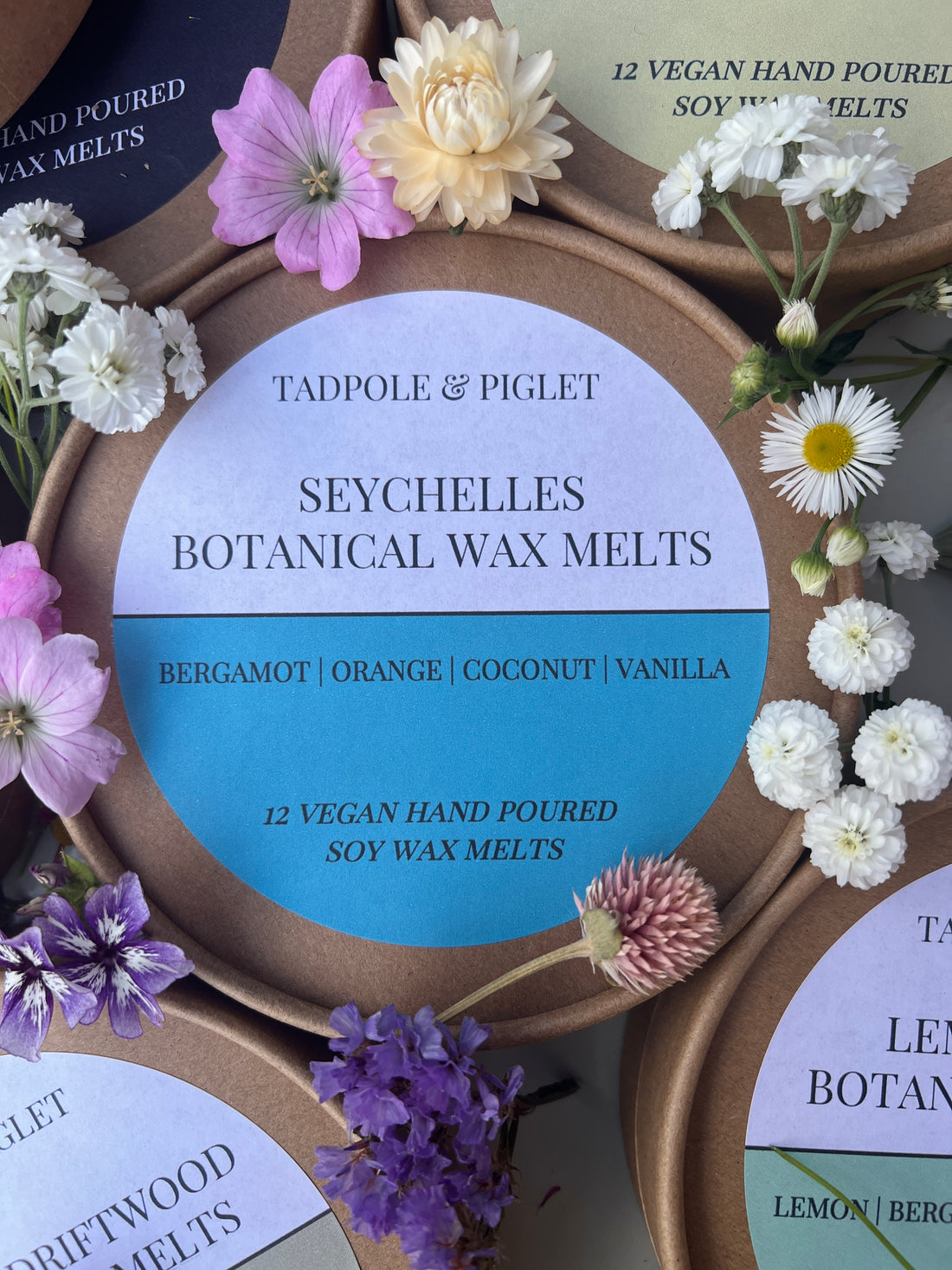 Seychelles Botanical Wax Melts surrounded by flowers, featuring bergamot, orange, coconut, and vanilla notes. Vegan hand poured soy wax melts.