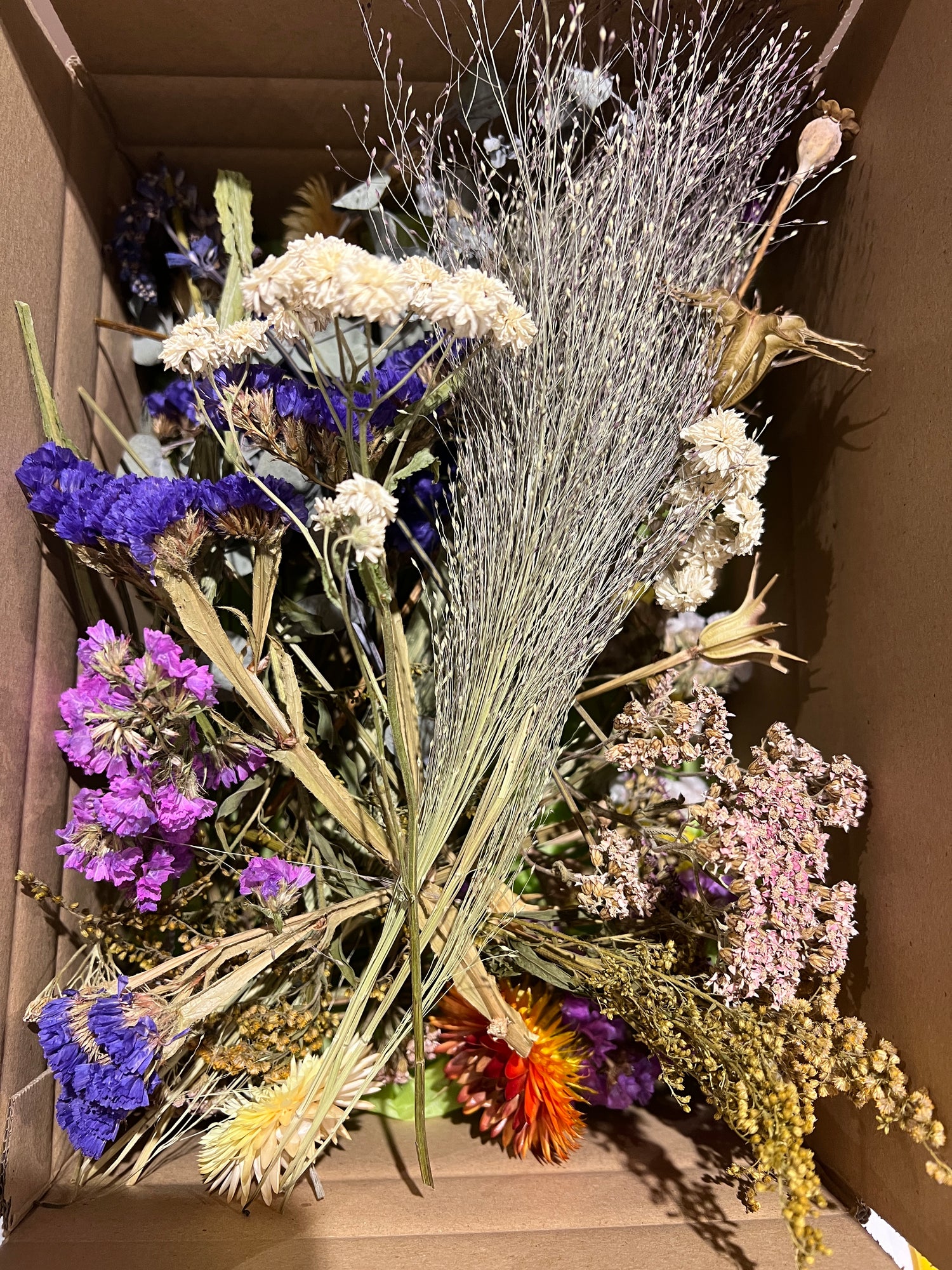 Box filled with vibrant dried flowers, including strawflowers, statice, and bunny tails, perfect for crafts.